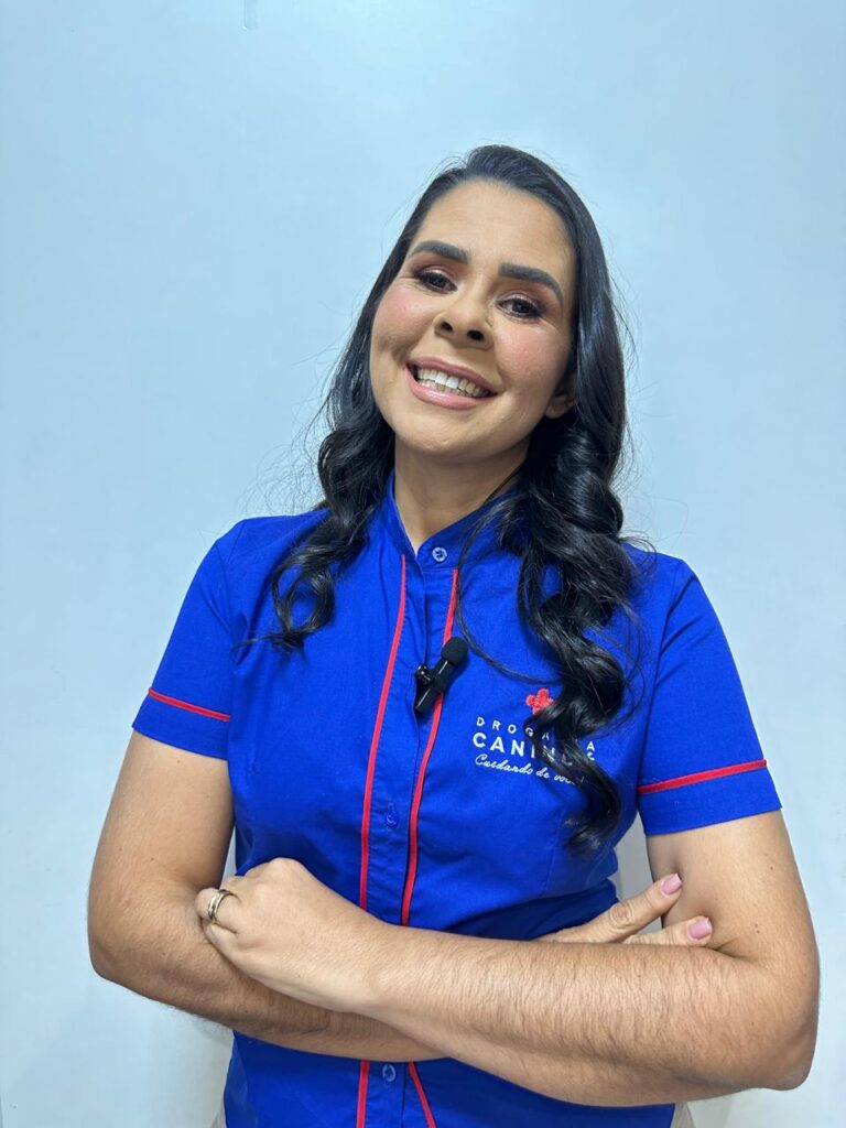 Dra. Raphaelle Ribeiro, sorrindo com o uniforme da Drogaria Canindé. Conheça a história da nossa farmácia com mais de 40 anos de tradição em Natal, RN.